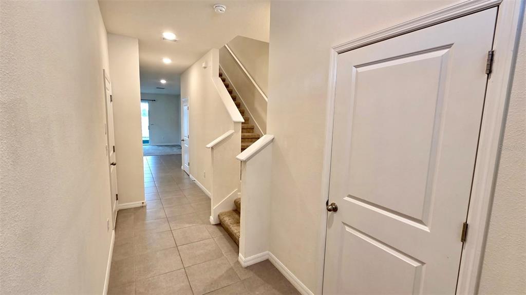 An interior hallway features tile flooring, a carpeted staircase, and several white interior doors — 1737 HOVENWEEP ROAD, WESLEY CHAPEL, FL