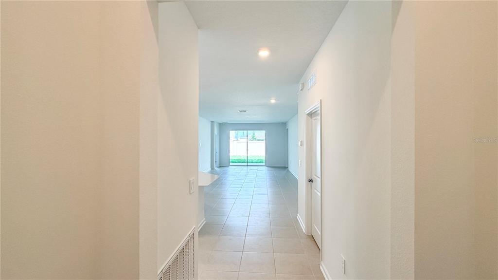 A view from a hallway looking into an open-concept living area with tile flooring — 5177 GREEN BELT DRIVE, HAINES CITY, FL