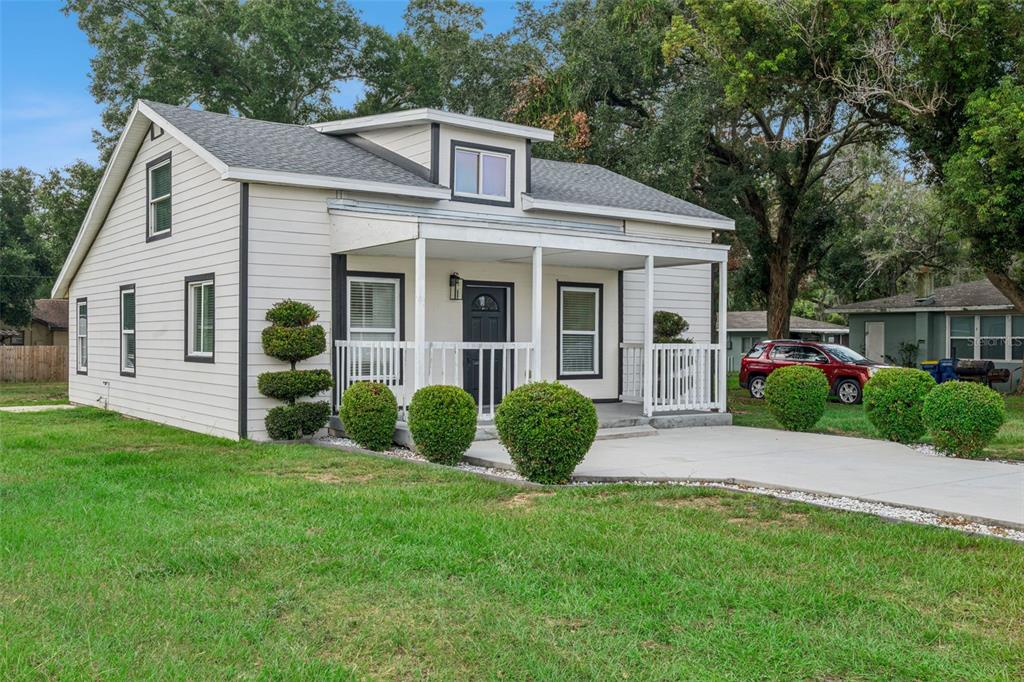 A white house with a front porch, dark trim, and a manicured lawn — 306 S DISSTON AVENUE, MINNEOLA, FL