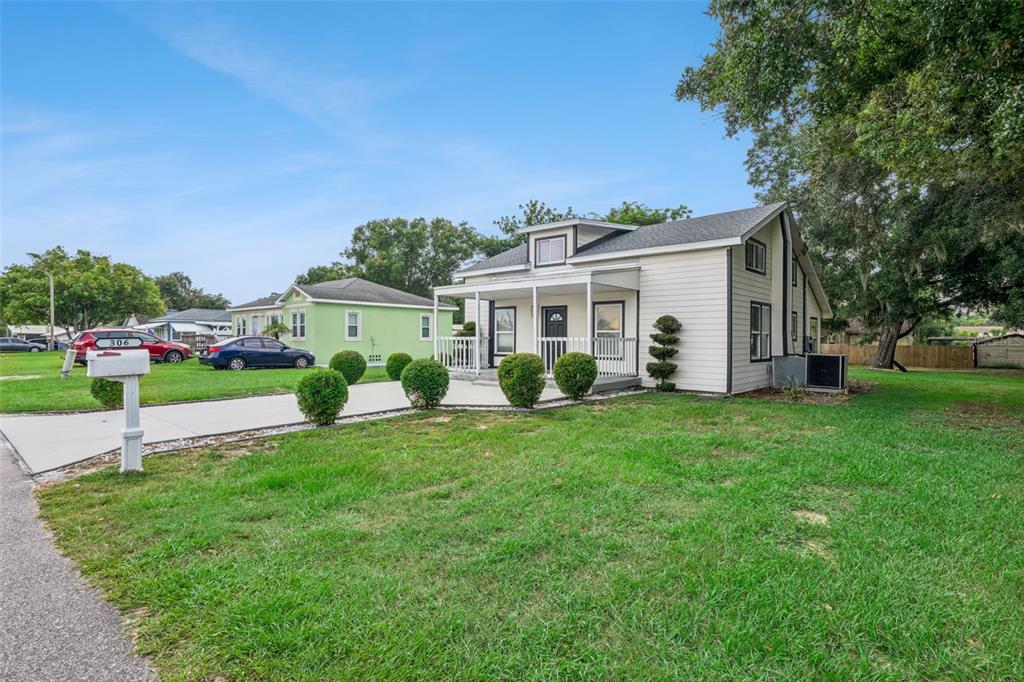 A light-colored house with a front porch and a concrete driveway sits on a lawn — 306 S DISSTON AVENUE, MINNEOLA, FL