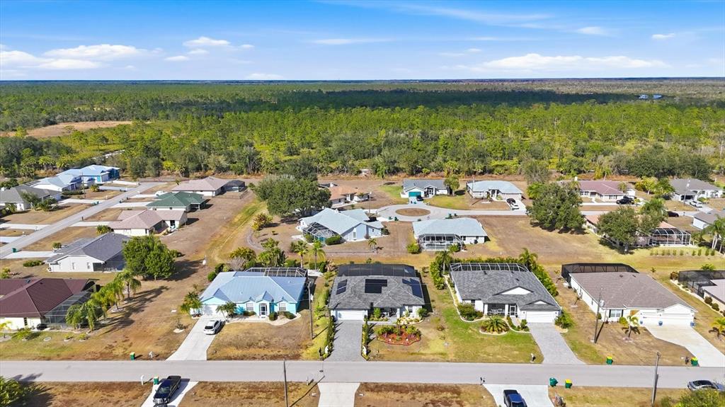 An aerial view shows a suburban neighborhood with single-family homes surrounded by a wooded area — 27052 TIERRA DEL FUEGO CIRCLE, PUNTA GORDA, FL