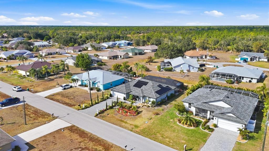 An aerial view shows a suburban neighborhood with single-family homes and surrounding wooded areas — 27052 TIERRA DEL FUEGO CIRCLE, PUNTA GORDA, FL