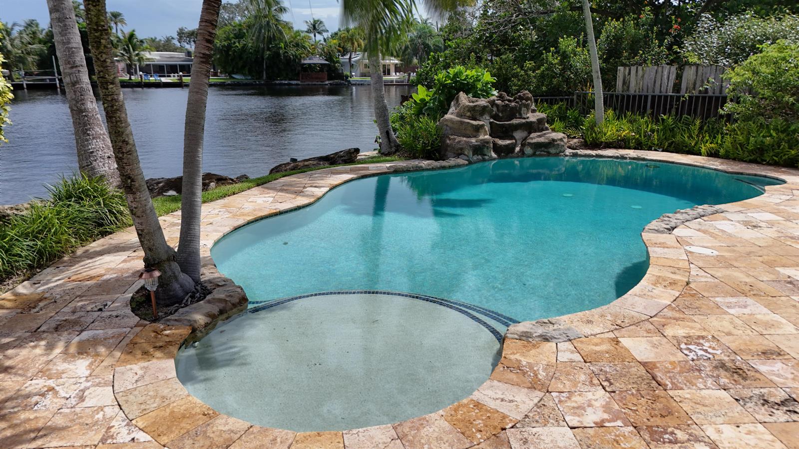 A swimming pool with a connected spa and rock waterfall overlooks a canal — 1925 Coral Gardens Drive, Wilton Manors FL 33306, WILTON MANORS, FL