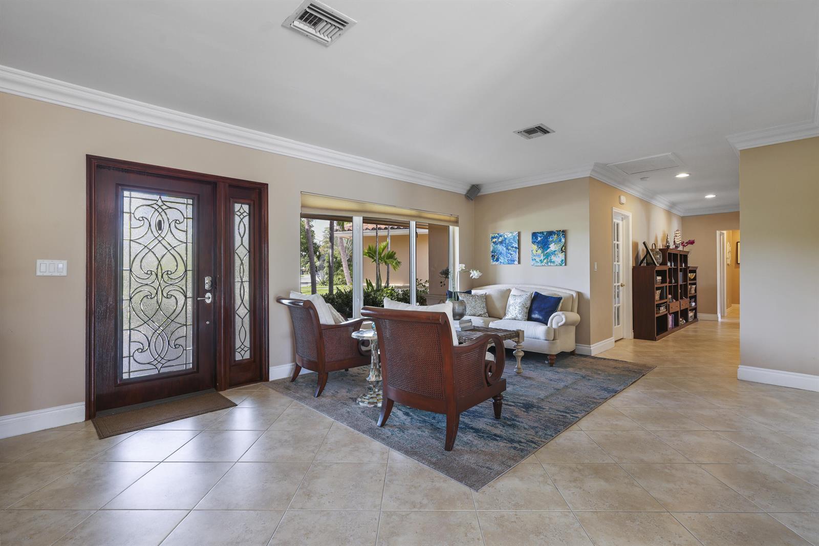 A living room features tile floors, a dark wood front door, and a seating area — 1925 Coral Gardens Drive, Wilton Manors FL 33306, WILTON MANORS, FL