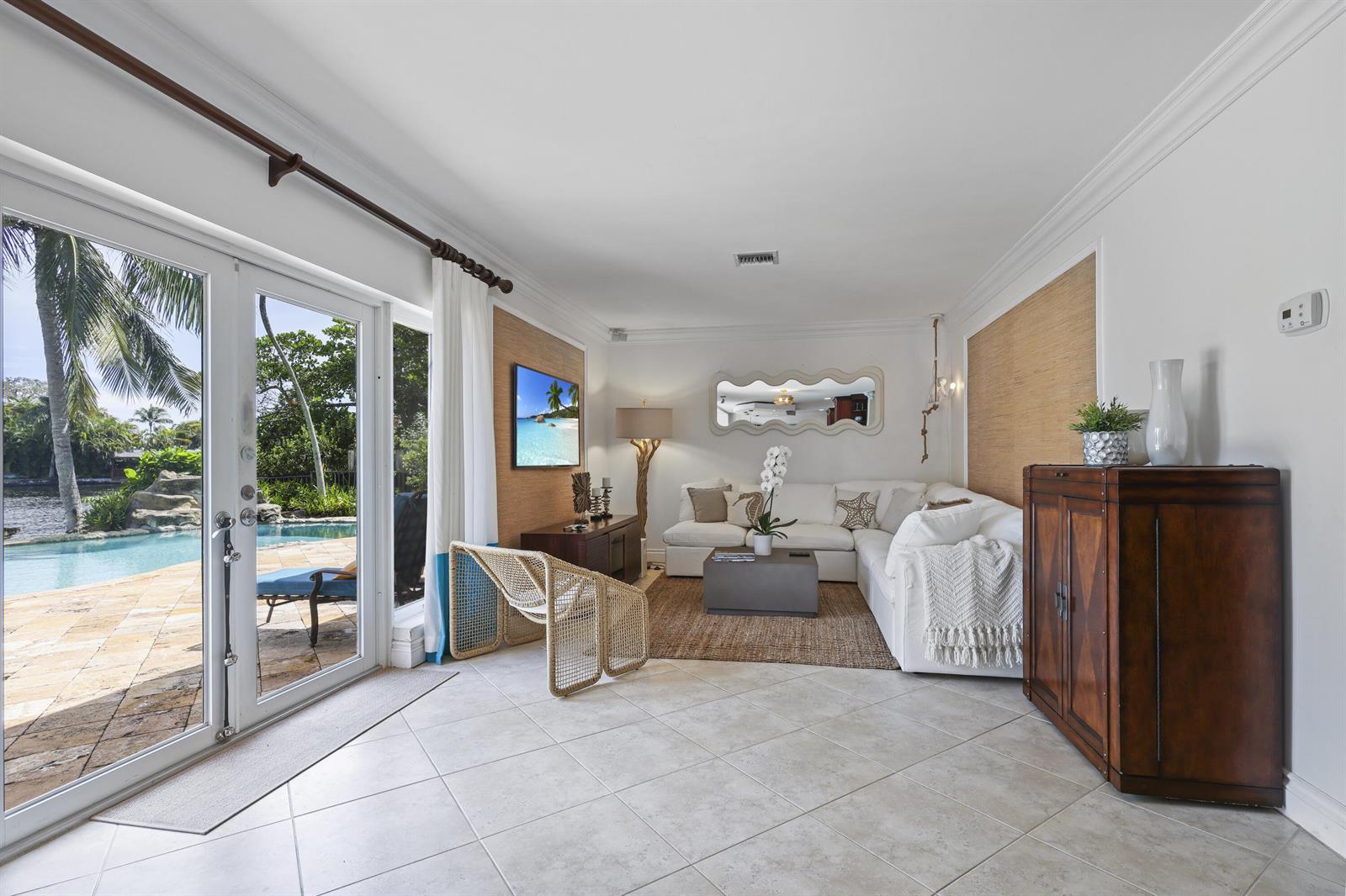 A living room with white walls, a sectional sofa, and glass doors opening to a pool — 1925 Coral Gardens Drive, Wilton Manors FL 33306, WILTON MANORS, FL