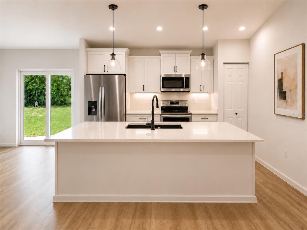 A modern open-concept living room and kitchen featuring light wood floors and neutral furniture — 14575 SW 20TH PLACE, OCALA, FL