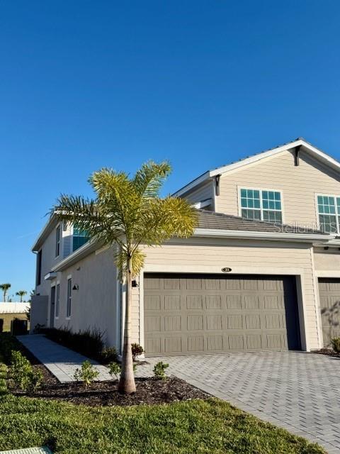 A two-story house features a tan exterior, a two-car garage, and a palm tree — 17735 BORACAY COURT UNIT 101, VENICE, FL