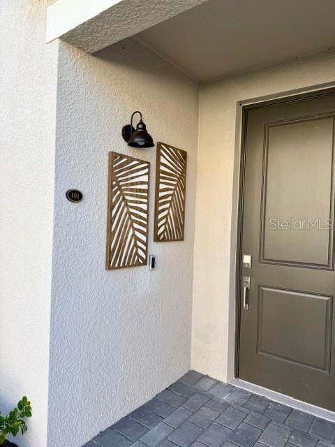 A front entryway features a dark door, two decorative wall panels, and a wall-mounted light — 17735 BORACAY COURT UNIT 101, VENICE, FL