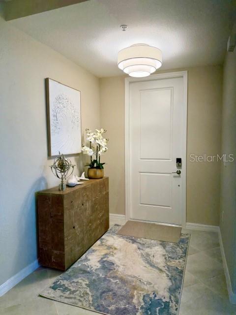 A foyer features a wooden console table, a patterned rug, and a white entry door — 17735 BORACAY COURT UNIT 101, VENICE, FL