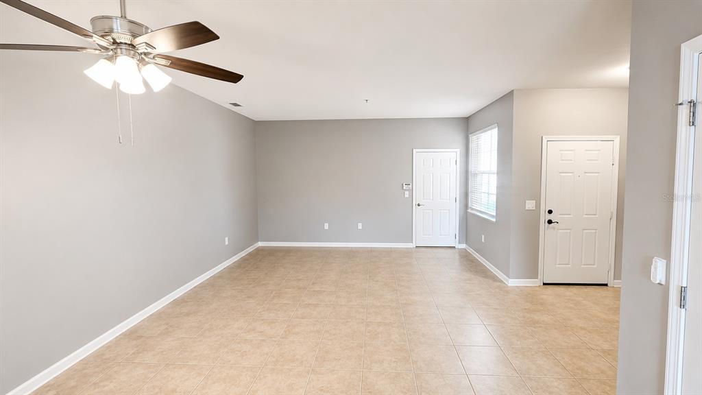 An empty living room with light gray walls, tile flooring, and a ceiling fan — 3696 PARKRIDGE CIRCLE UNIT 26-105, SARASOTA, FL