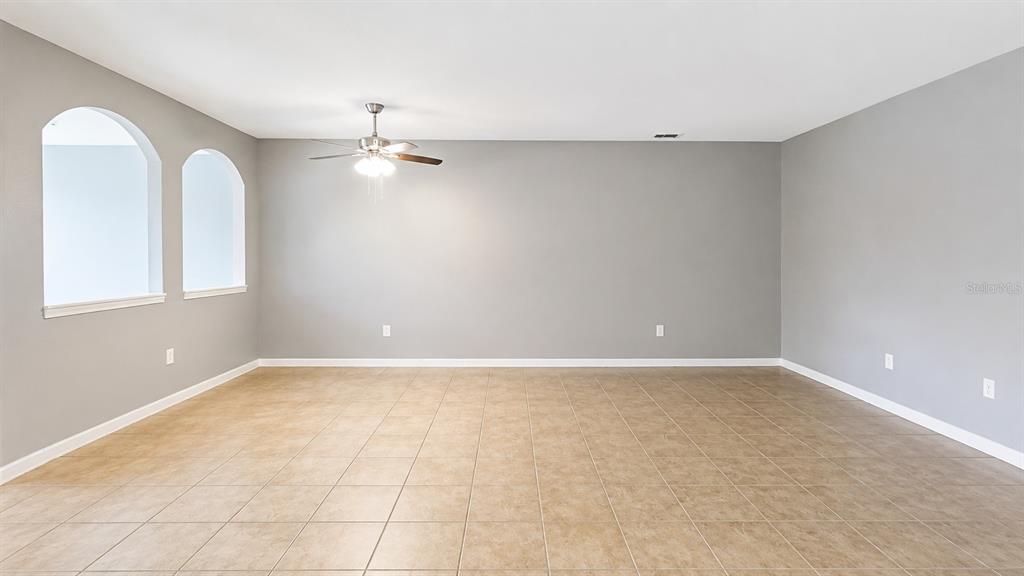 An empty room features light gray walls, tan tile flooring, and two arched windows — 3696 PARKRIDGE CIRCLE UNIT 26-105, SARASOTA, FL