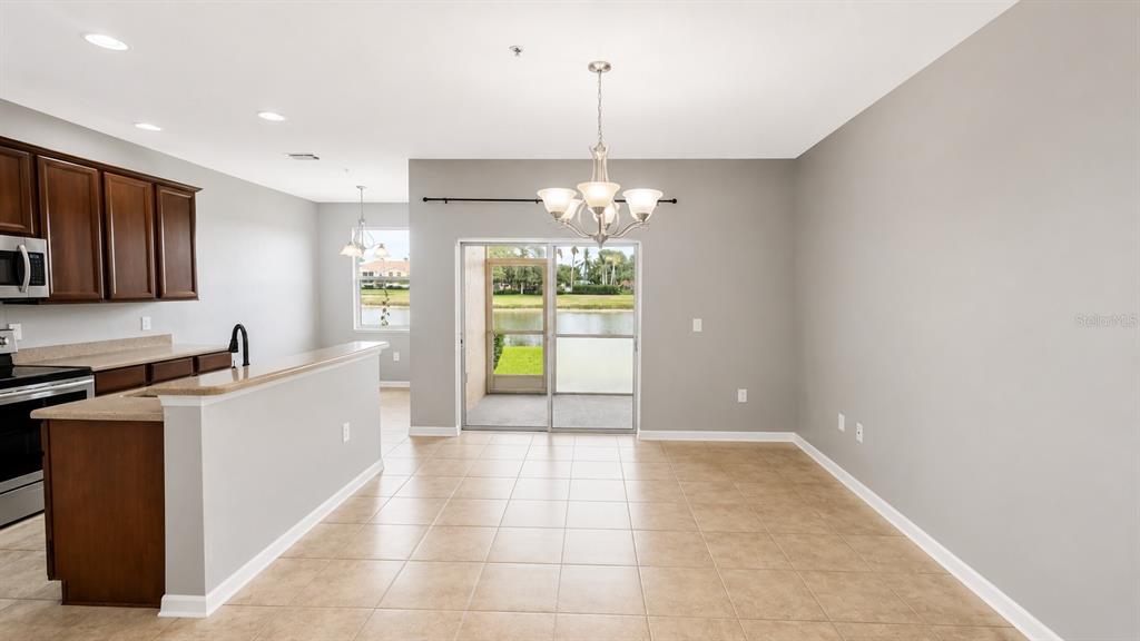 A kitchen with dark wood cabinets and a dining area featuring a sliding glass door — 3696 PARKRIDGE CIRCLE UNIT 26-105, SARASOTA, FL