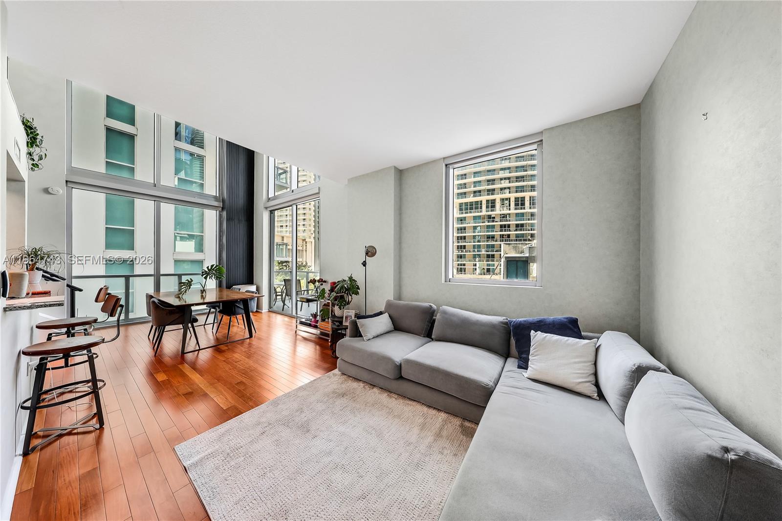 A living room with hardwood floors, a gray sectional sofa, and floor-to-ceiling windows — 1050 Brickell Ave # 422, Miami FL 33131, MIAMI, FL