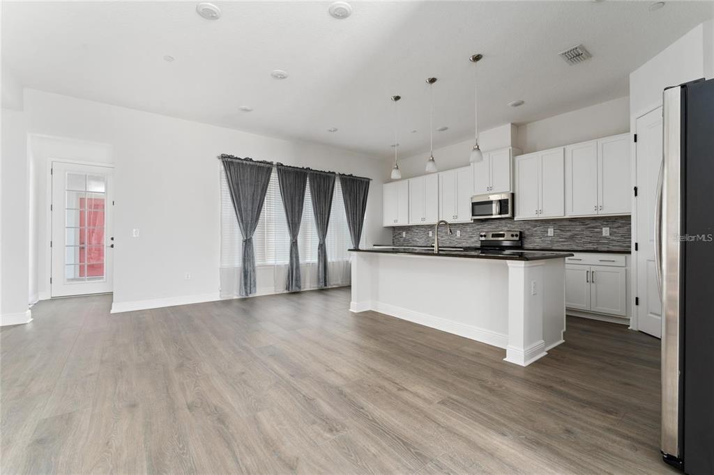A kitchen with white cabinets, a central island, and wood-look flooring in an open space — 13427 STODDART AVENUE, ORLANDO, FL