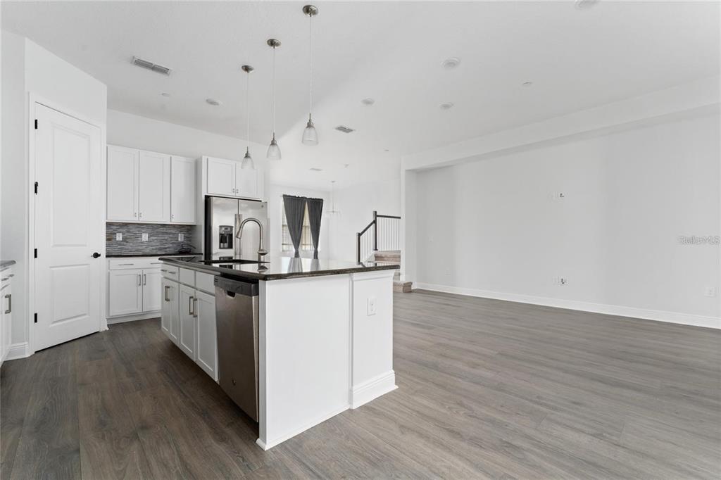 A modern kitchen with white cabinets, a central island, and wood-look flooring — 13427 STODDART AVENUE, ORLANDO, FL