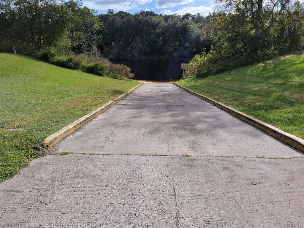 A concrete boat ramp leads down to a dark body of water surrounded by trees — SE 74TH LANE ROAD UNIT 9-WEST, OCKLAWAHA, FL