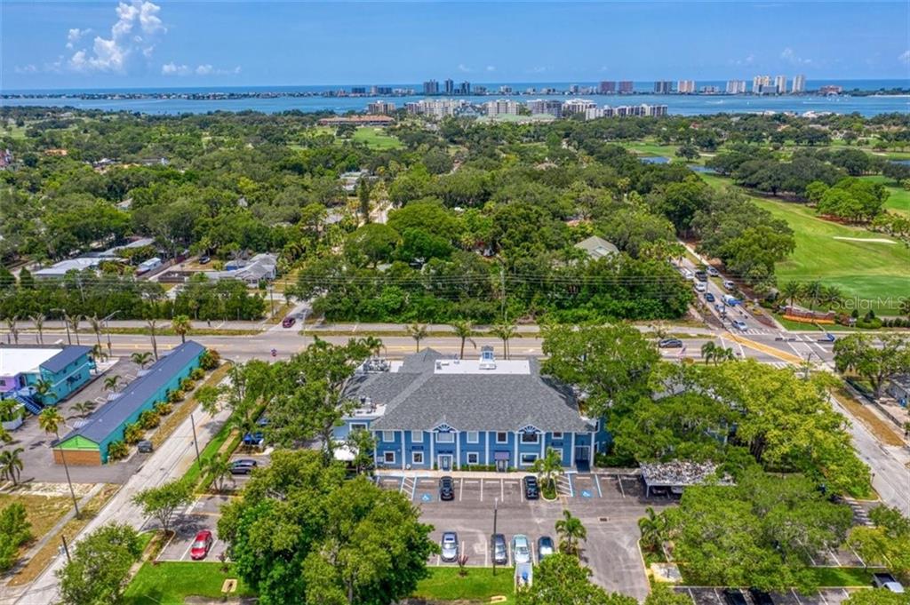 An aerial view shows a blue commercial building with a parking lot and surrounding greenery — 1465 S FORT HARRISON AVENUE, CLEARWATER, FL