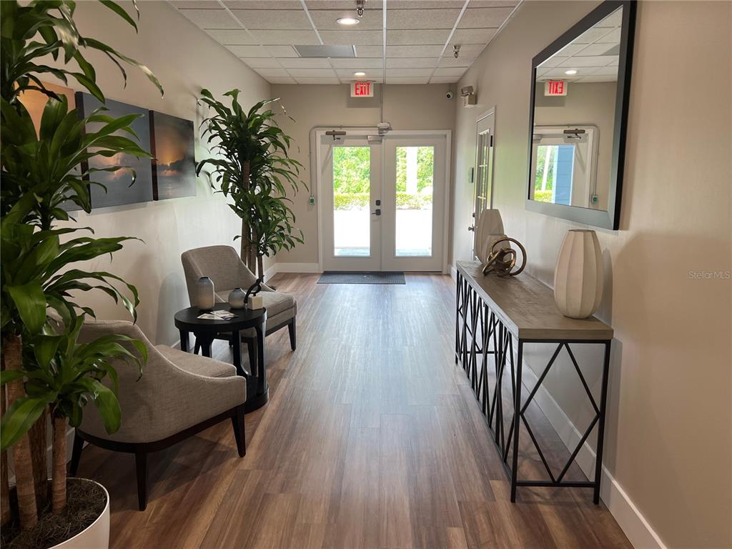 A modern lobby features wood-look flooring, two armchairs, a console table, and double glass doors — 1465 S FORT HARRISON AVENUE, CLEARWATER, FL