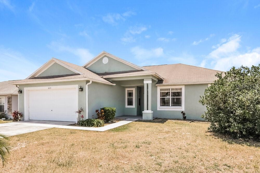 A light green single-story house with a two-car garage and a covered front entryway — 6033 LIVE OAK DRIVE, WINTER HAVEN, FL