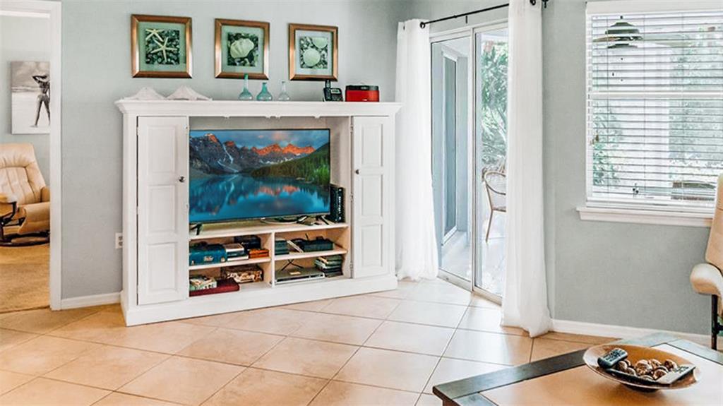 A living room features a white entertainment center, tile flooring, and a sliding glass door — 1272 SIESTA BAYSIDE DRIVE UNIT 1272-C, SARASOTA, FL