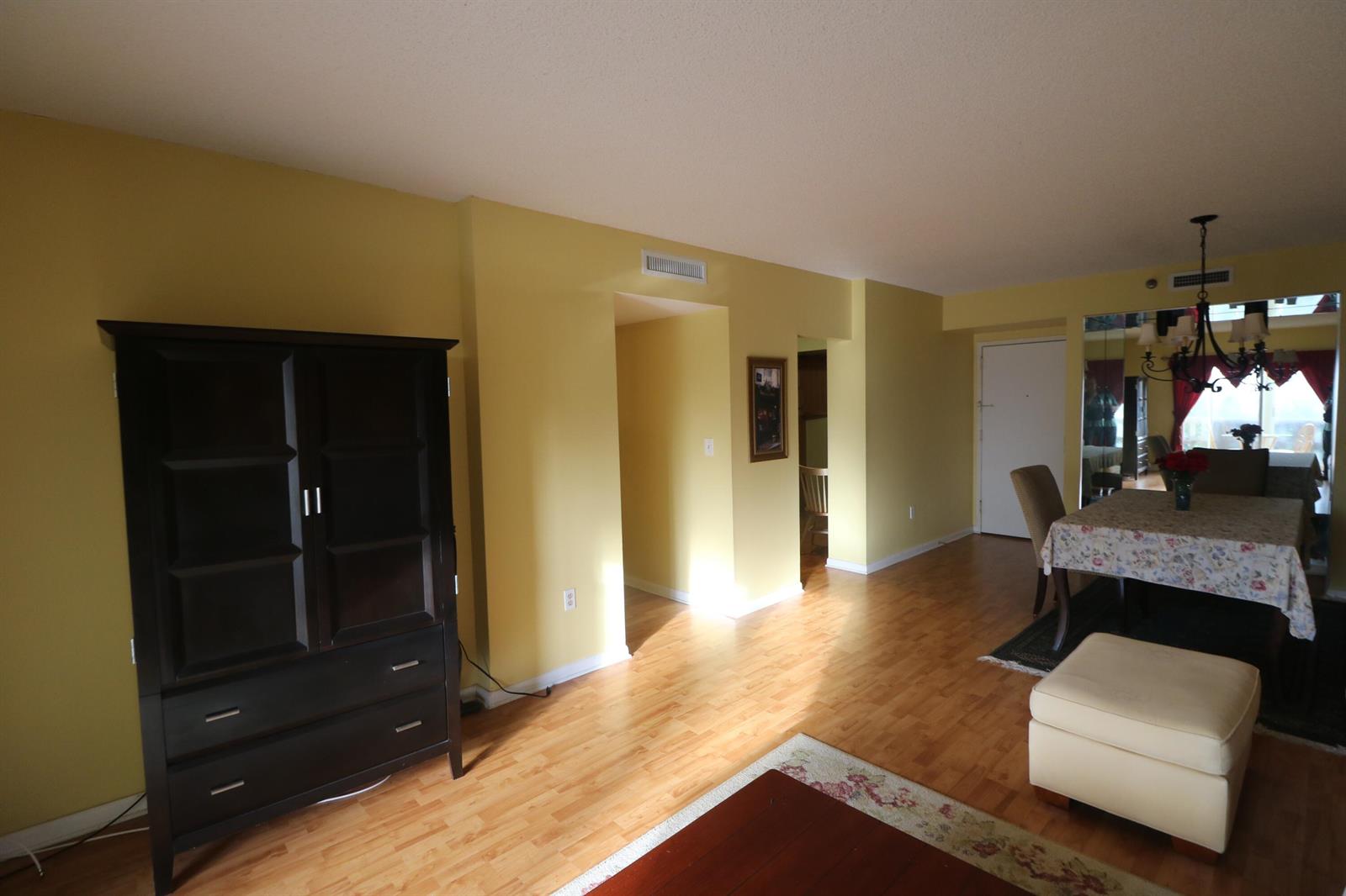 A living and dining area with yellow walls, hardwood floors, and a dark wood cabinet — 4001 Hillcrest Drive # 510, Hollywood FL 33021, HOLLYWOOD, FL