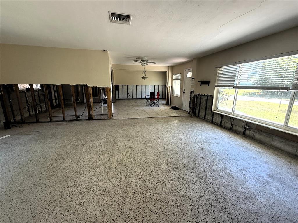 An unfinished living area features exposed wall studs, concrete flooring, and large windows — 102 158TH AVENUE, REDINGTON BEACH, FL
