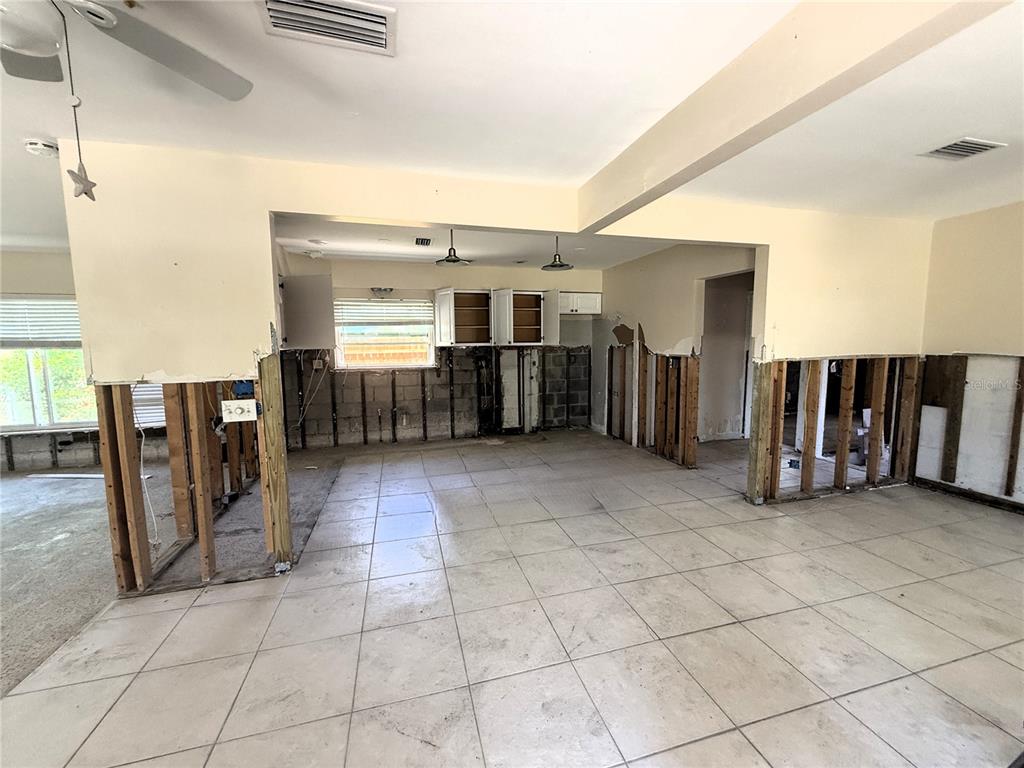 An interior view of a kitchen and living area undergoing renovation with exposed wall studs — 102 158TH AVENUE, REDINGTON BEACH, FL