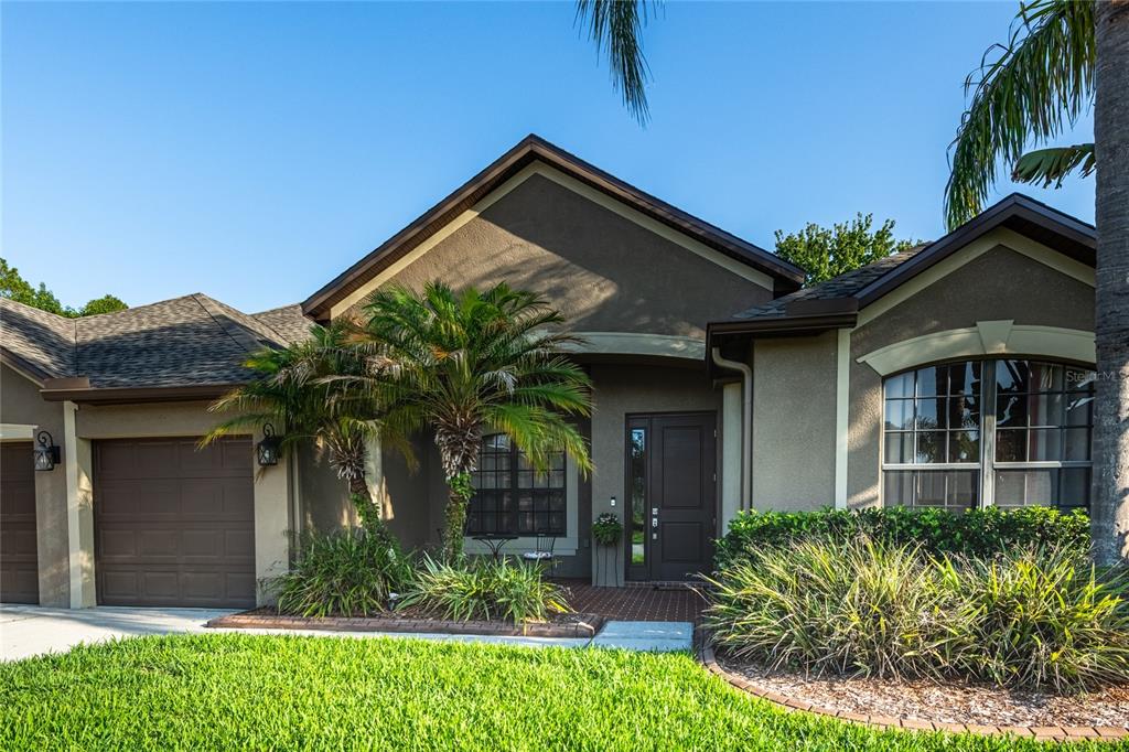 A single-story house with a brown garage, a front entrance, and a landscaped yard — 14815 NINEBARK COURT, LAND O LAKES, FL
