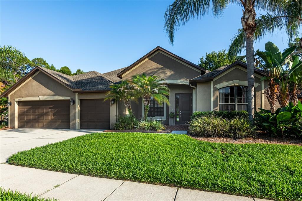 A single-story house with a brown exterior, two garage doors, and a landscaped front yard — 14815 NINEBARK COURT, LAND O LAKES, FL
