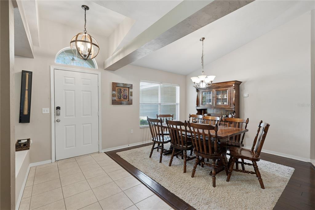 A dining room with a wooden table and chairs sits on a rug near an entryway — 1003 NW 106TH STREET, GAINESVILLE, FL
