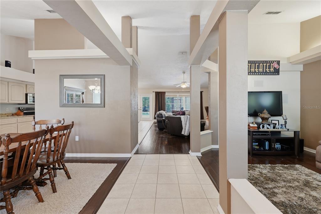 A dining area with a mirror leads to a living room with dark wood floors — 1003 NW 106TH STREET, GAINESVILLE, FL