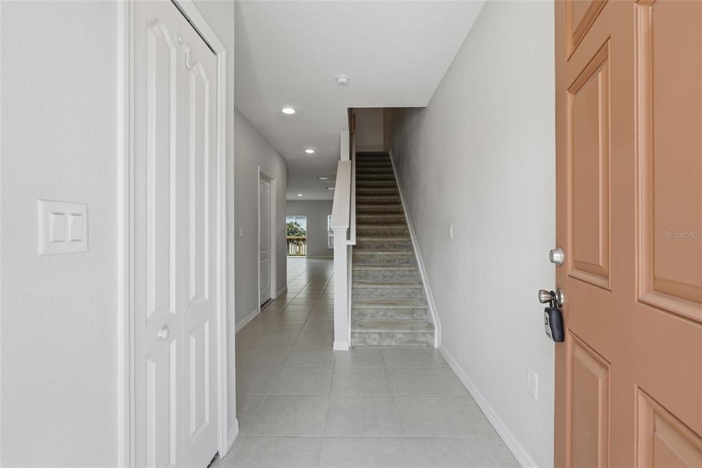 An entryway features a tiled floor, a carpeted staircase, and a white door on the left — 3857 HAMPSTEAD LANE, LAKELAND, FL
