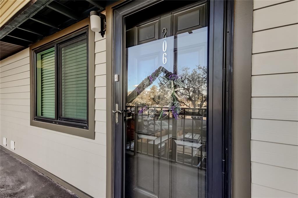 A dark-framed glass storm door with the number 206 sits beside a window on a building — 650 ISLAND WAY UNIT 206, CLEARWATER BEACH, FL