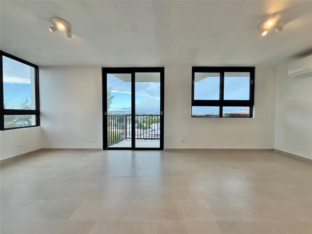 An unfurnished room with light tile floors, large windows, a sliding glass door, and balcony — 1 CALLE INGA UNIT 8D, SAN JUAN, PR