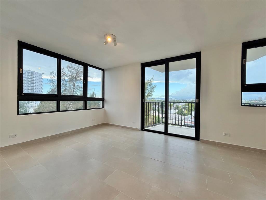 An empty room with light tile floors, large windows, and a sliding door to a balcony — 1 CALLE INGA UNIT 8D, SAN JUAN, PR