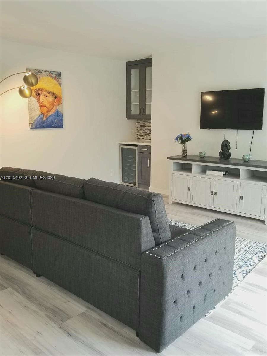 A living room features a dark gray sofa, a wet bar, and a sliding glass door — 1601 Bay Rd # 7, Miami Beach FL 33139, MIAMI BEACH, FL