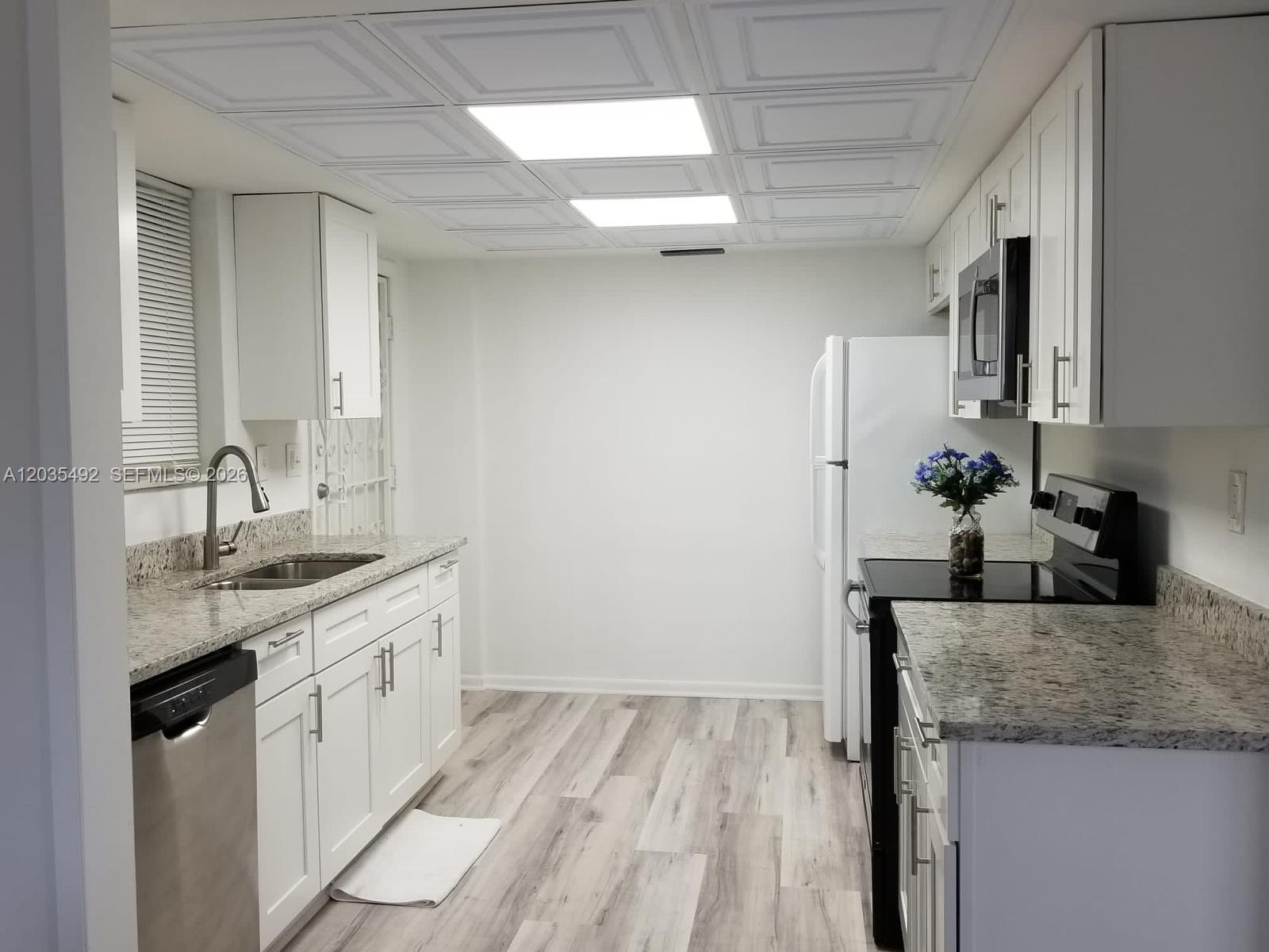 A bedroom features a bed, a ceiling fan, an attached bathroom, and a laundry unit — 1601 Bay Rd # 7, Miami Beach FL 33139, MIAMI BEACH, FL
