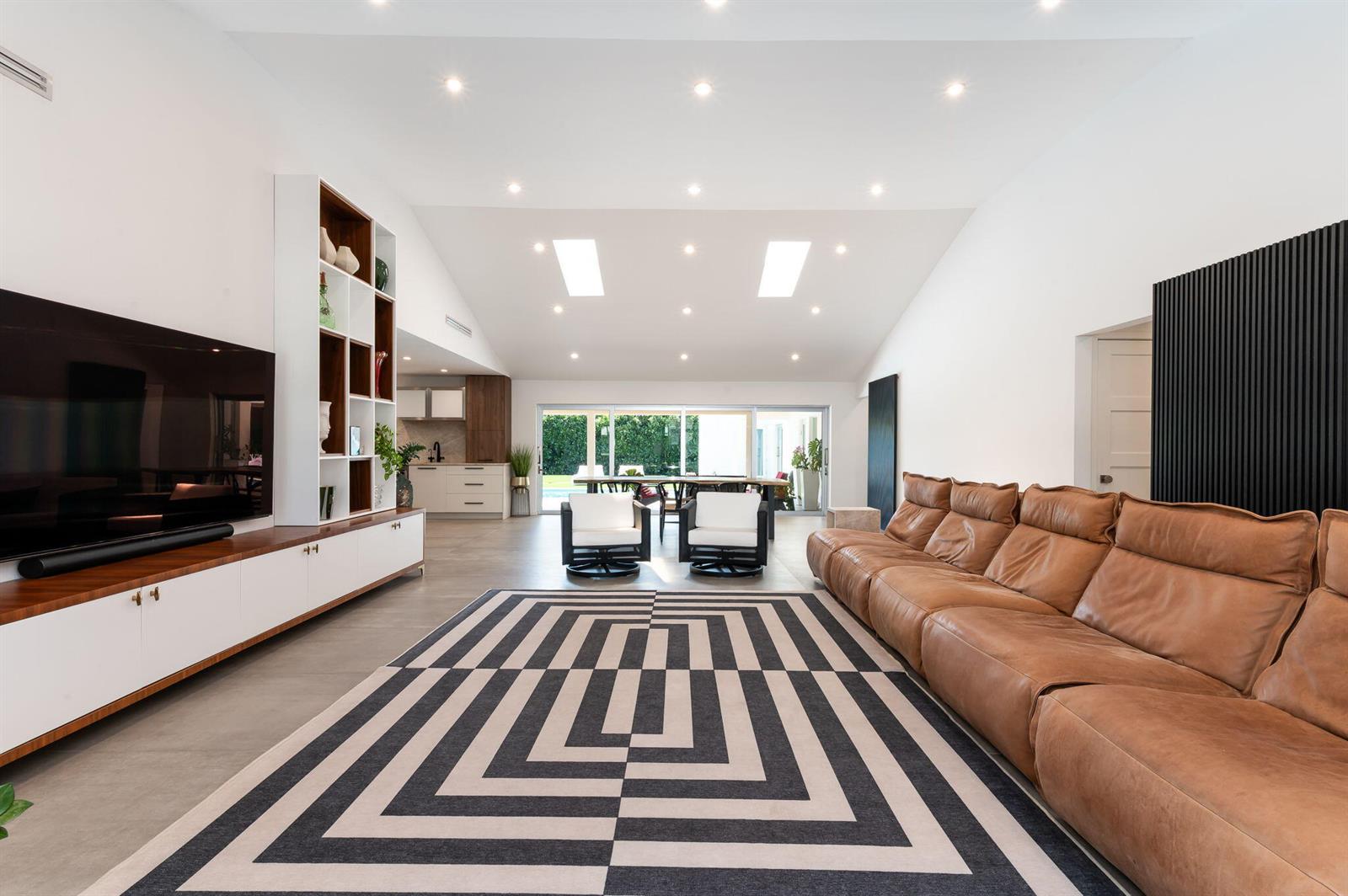 A spacious living room features a large leather sofa, geometric rug, and vaulted ceiling — 1398 SW 14th Street, Boca Raton FL 33486, BOCA RATON, FL