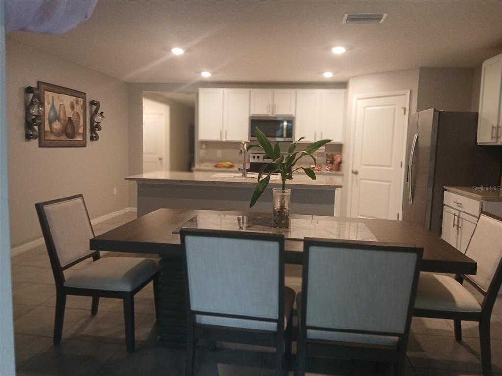 A dining area with a dark wood table and chairs sits before an open kitchen — 3719 CAPRI COAST DRIVE, PLANT CITY, FL