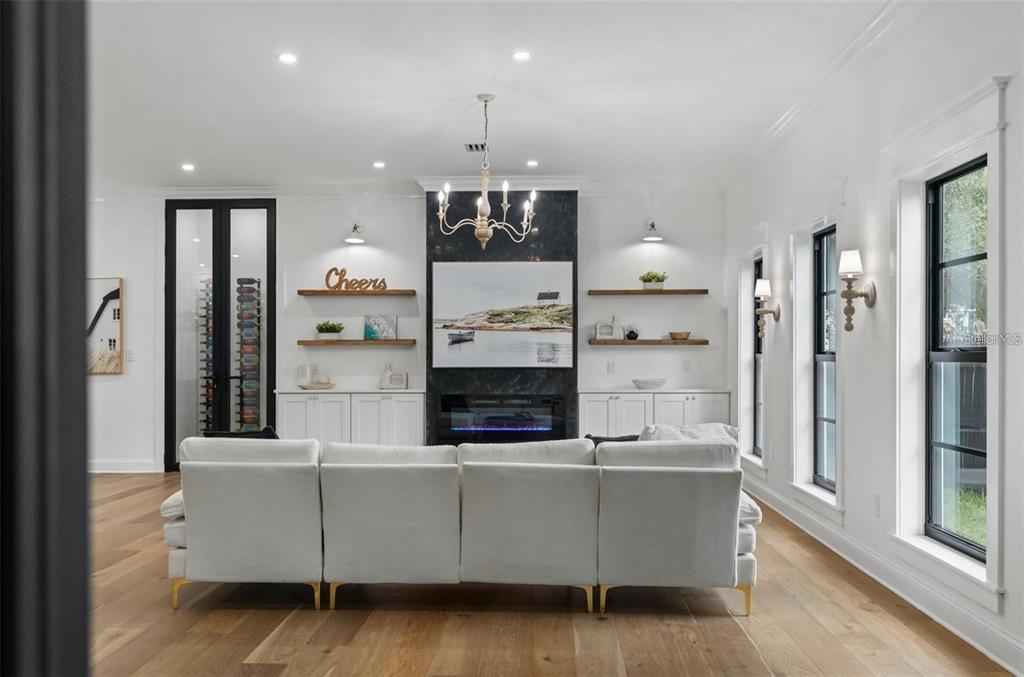 A bright living room features a white sectional sofa, fireplace, and built-in shelving — 3501 W TACON STREET, TAMPA, FL