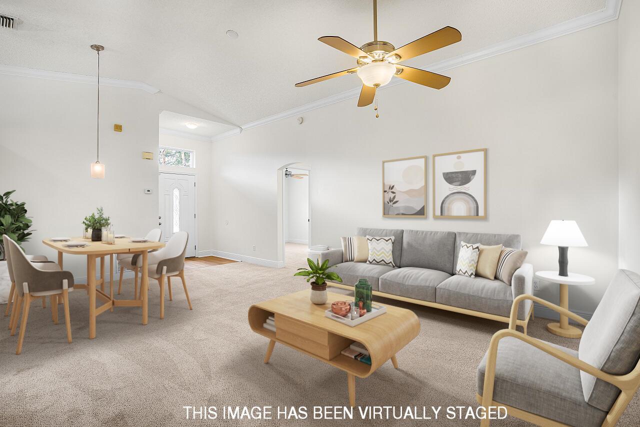 This virtually staged living and dining room features neutral carpeting, a ceiling fan, and furniture — 966 E 13th Square, Vero Beach FL 32960, VERO BEACH, FL