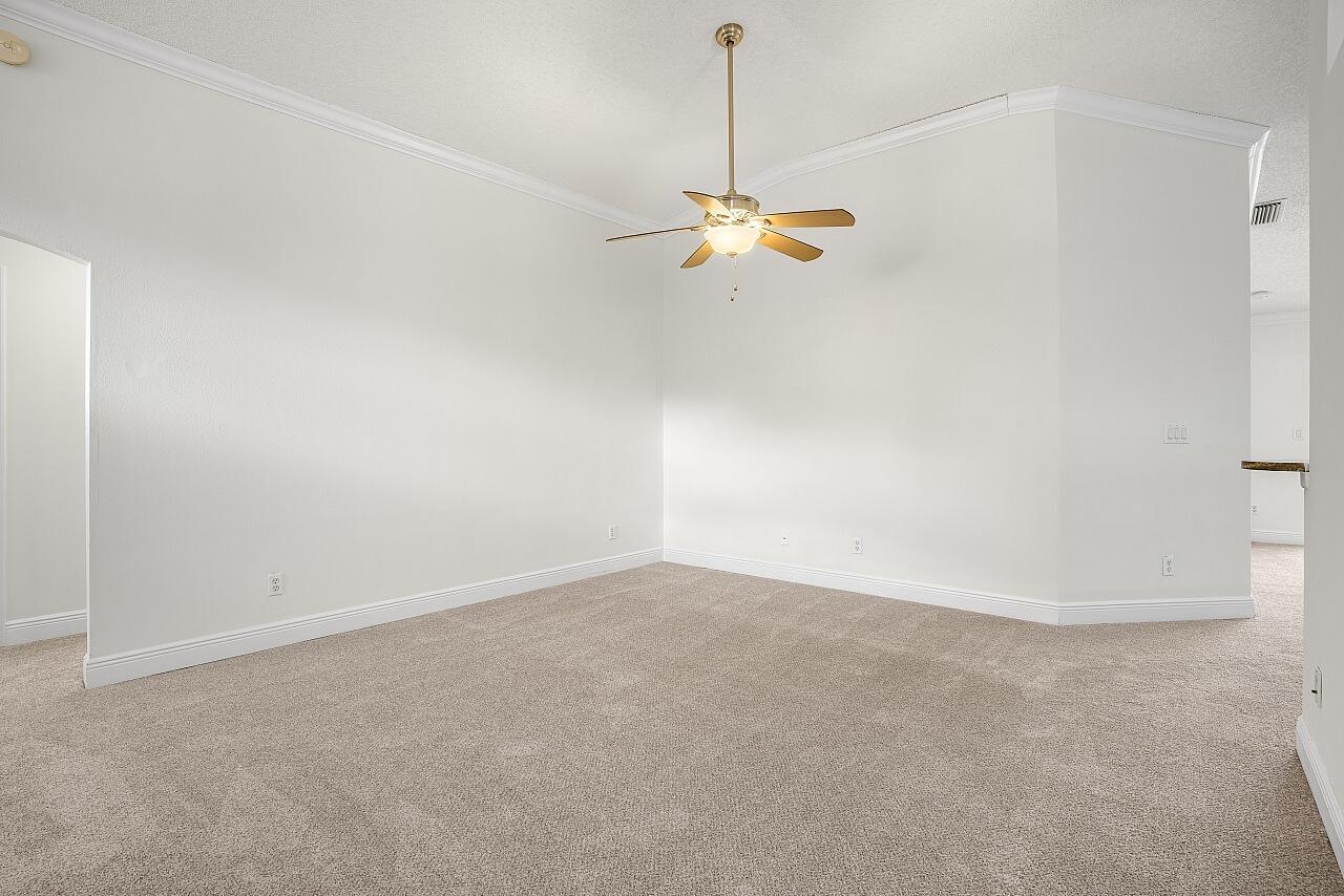 An empty room with beige carpet, white walls, crown molding, and a ceiling fan — 966 E 13th Square, Vero Beach FL 32960, VERO BEACH, FL