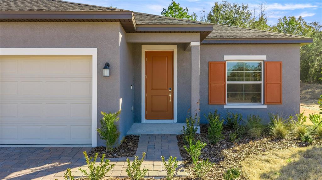 The exterior of a house features a garage, a front door, and a single window — 6664 SW 180TH CIRCLE, DUNNELLON, FL