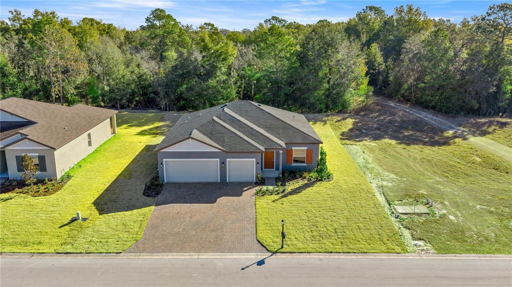 An aerial view shows a gray single-story house with a three-car garage and paved driveway — 6664 SW 180TH CIRCLE, DUNNELLON, FL