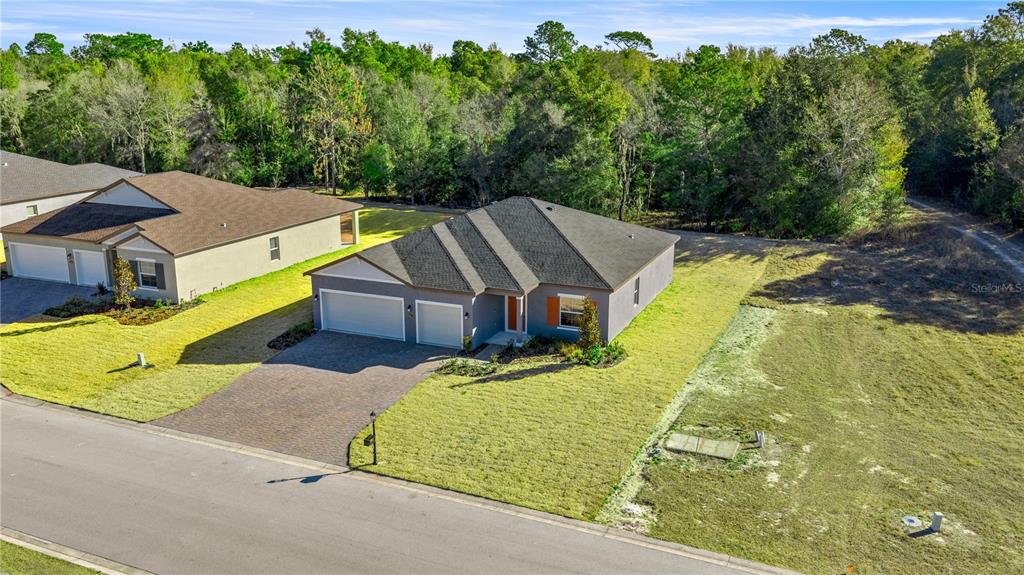 An aerial view shows a single-story house with a gray exterior and a paved driveway — 6664 SW 180TH CIRCLE, DUNNELLON, FL