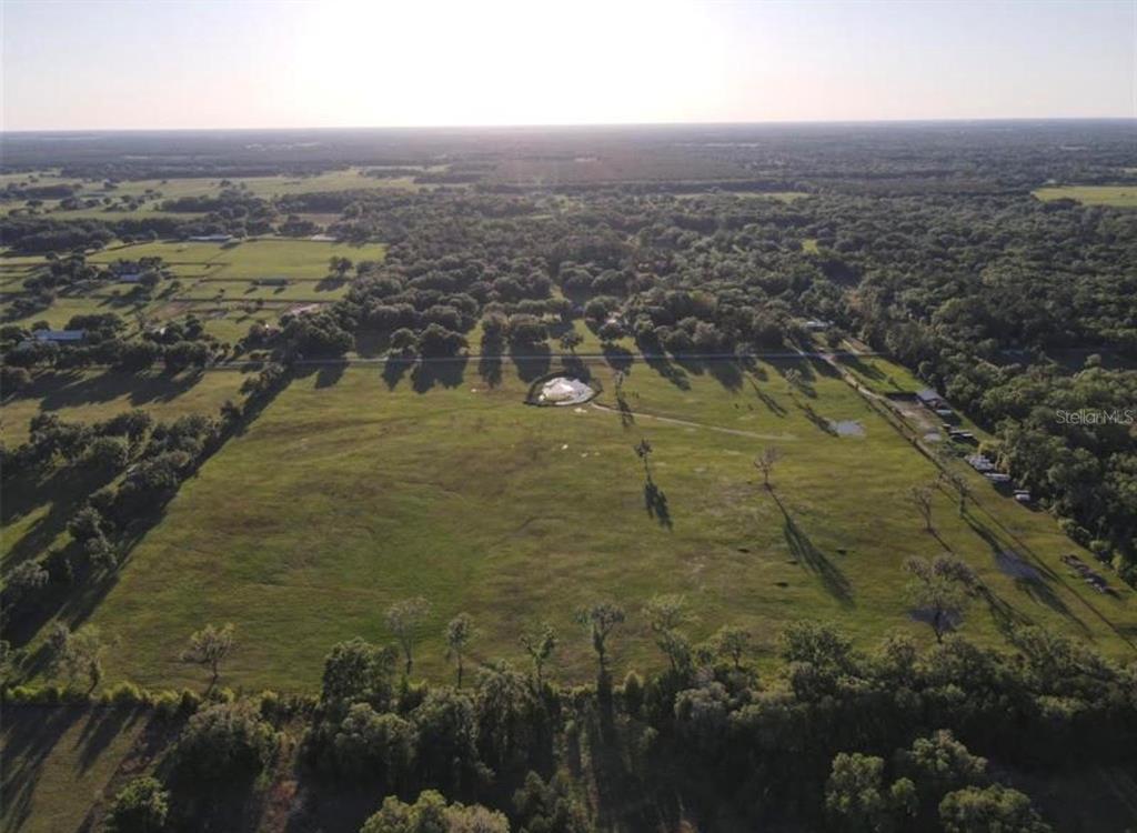 An aerial view shows a large, open grassy pasture surrounded by trees and rural land — NW 160 AVENUE, MORRISTON, FL