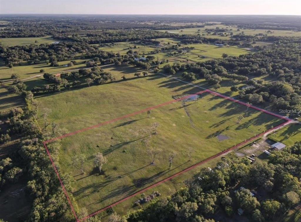 An aerial view shows a large, open grassy field outlined in red — NW 160 AVENUE, MORRISTON, FL