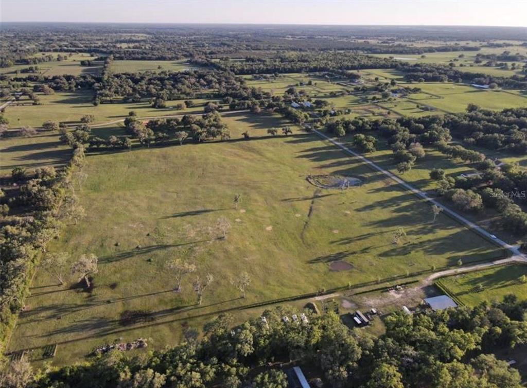 An aerial view of a large, open grassy pasture surrounded by trees and rural land — NW 160 AVENUE, MORRISTON, FL