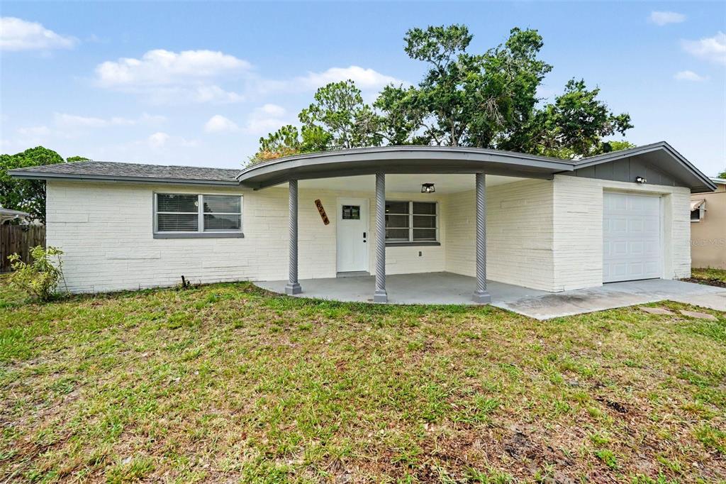 A single-story white brick house features a curved front porch with three decorative columns — 6244 6TH AVENUE, NEW PORT RICHEY, FL