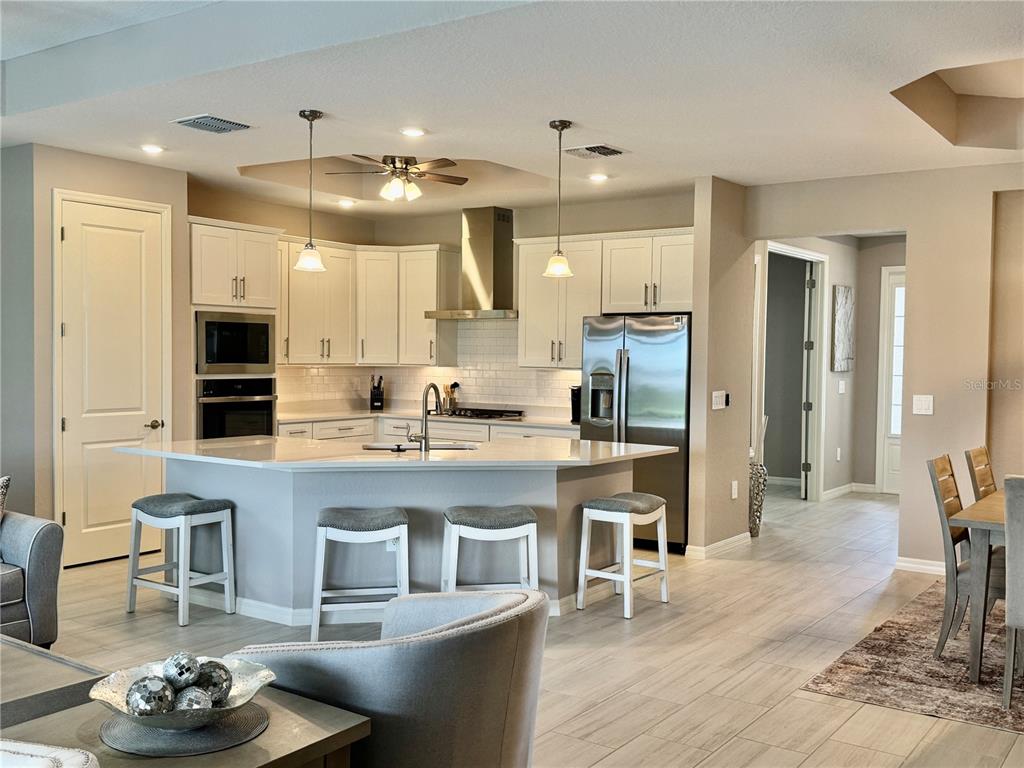 A modern kitchen features white cabinetry, stainless steel appliances, and a large central island — 19146 CHERRYSTONE WAY, LAKEWOOD RANCH, FL